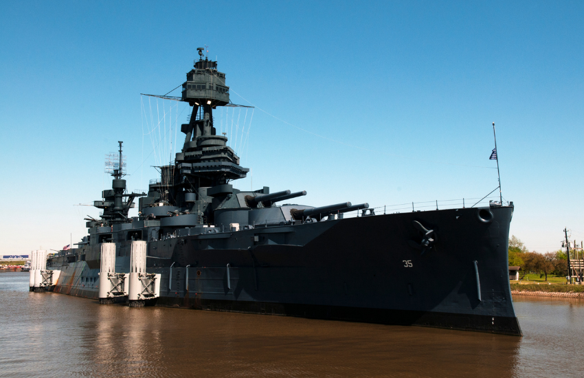 a battleship on brown water against a blue sky