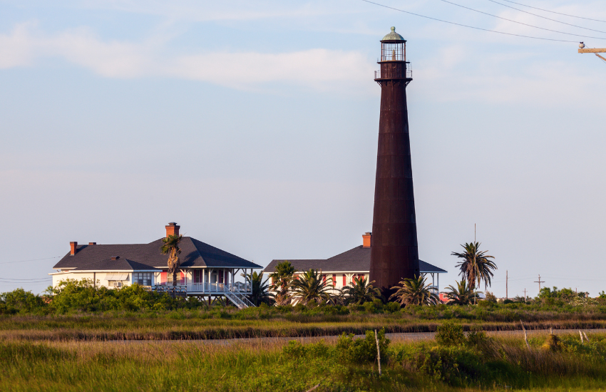 a lighthouse and two houses against a blue sky