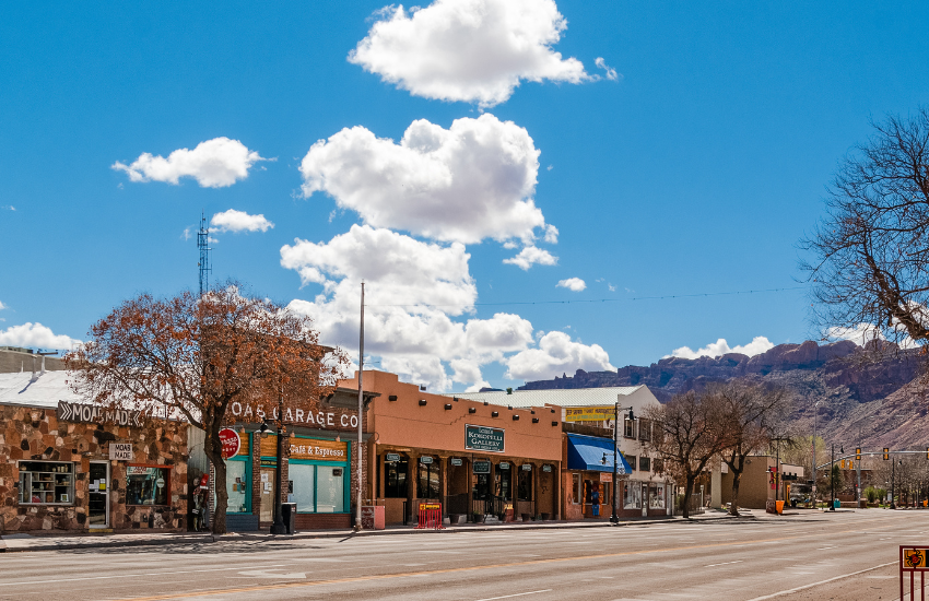 Moab Utah An empty stree with shops, a blue sky and mountains in the background.