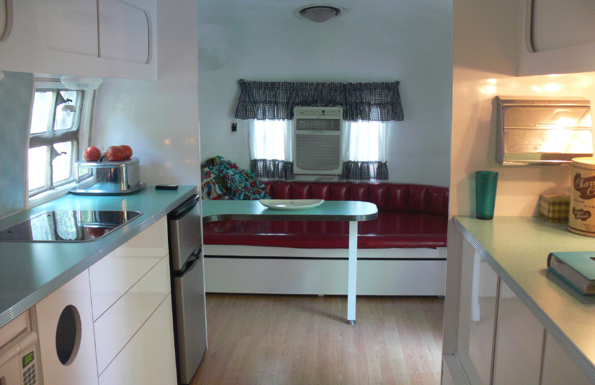 The inside of a camper with a red bench seat at the end.