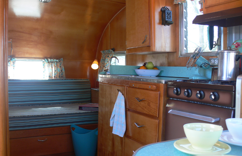Wooden RV kitchen with striped blue bench cushions.