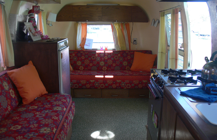 Inside an old camper with red floral bench seats.