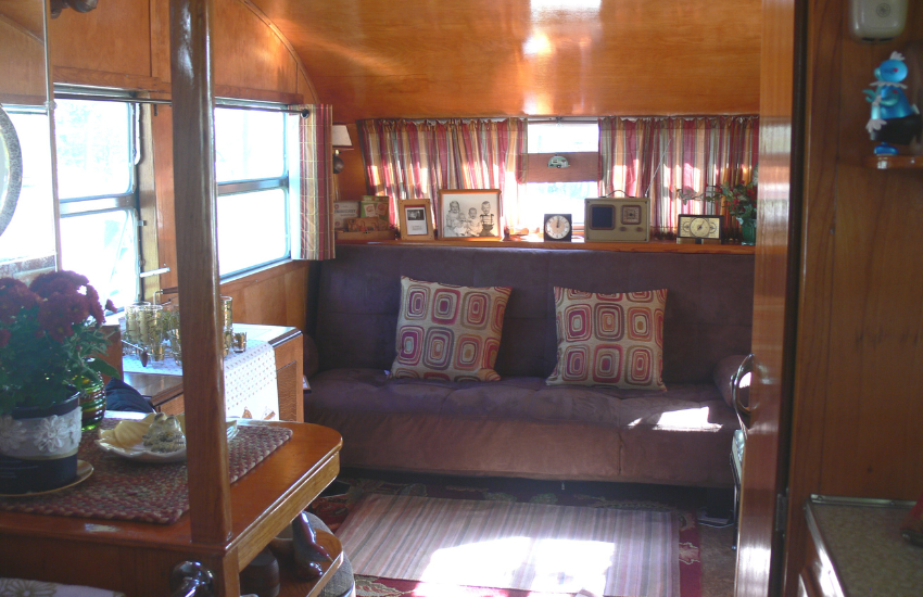 Vintage RV interior with purple seat and red stripey curtains.
