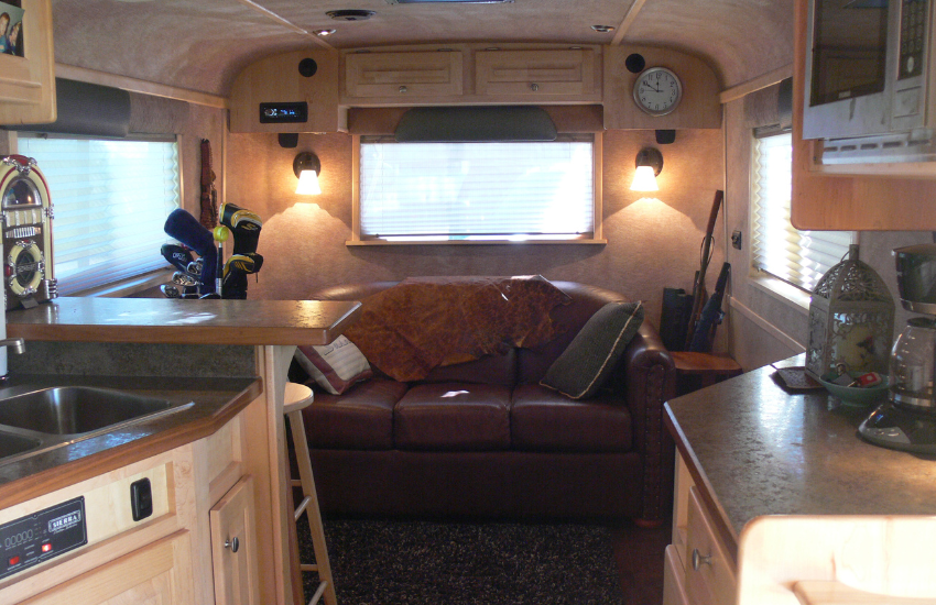 Old RV with a red leather sofa at the end of the living space.