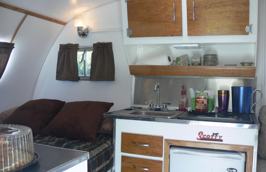 A kitchenette and sleeping area in a vintage camper.