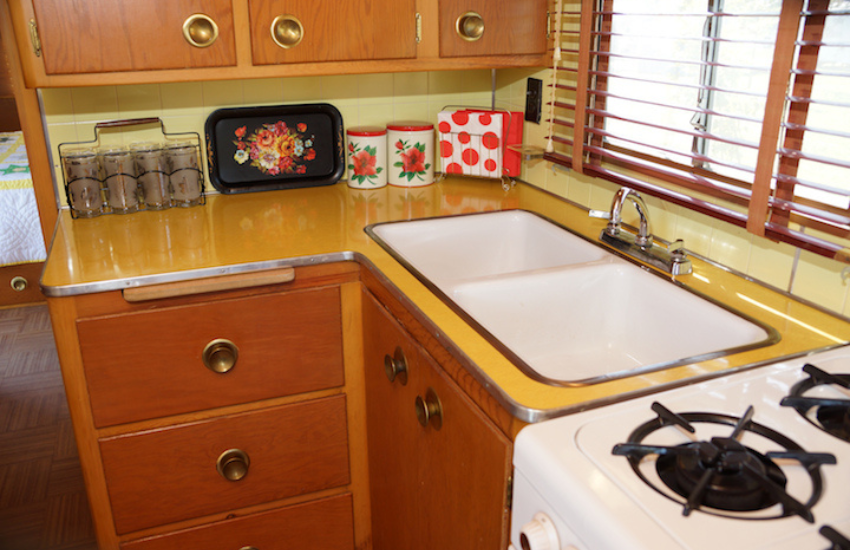 A beautiful old RV kitchen with white cooker and sink.