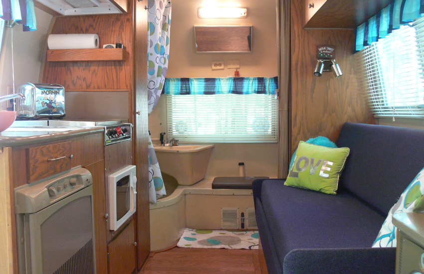 A vintage camper interior with blue stripey valances and dark blue seating.