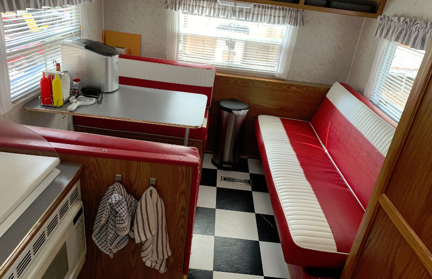 Red and white bench seats with a black and white chequred floor in an old camper.