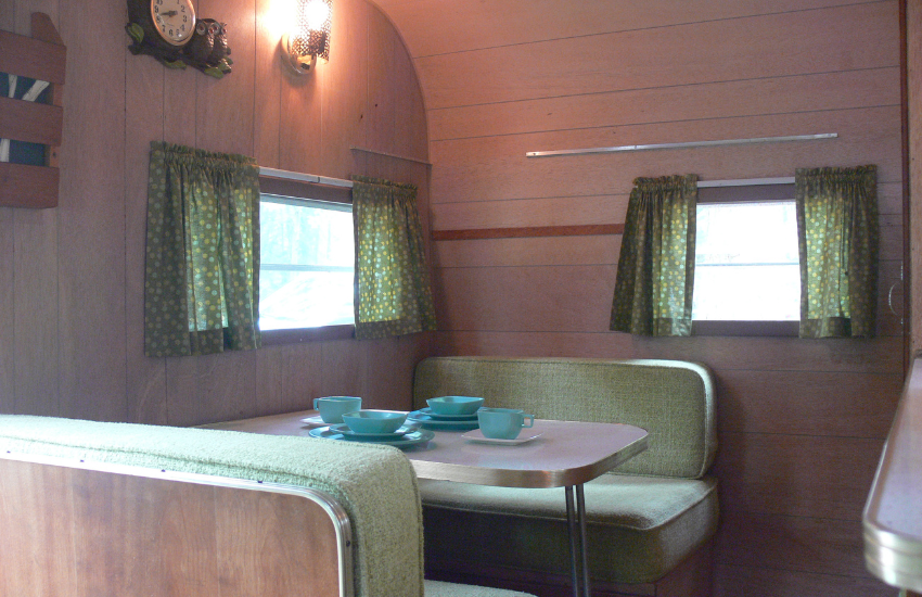 Green dinette seat cushions with matching curtains in an old RV.