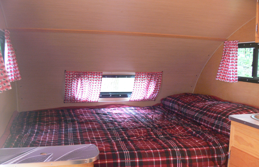 Red check bed and curtains in a vintage camper.