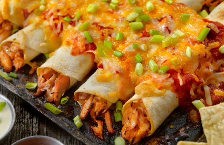 Chicken enchiladas with cheese and green onions on top.