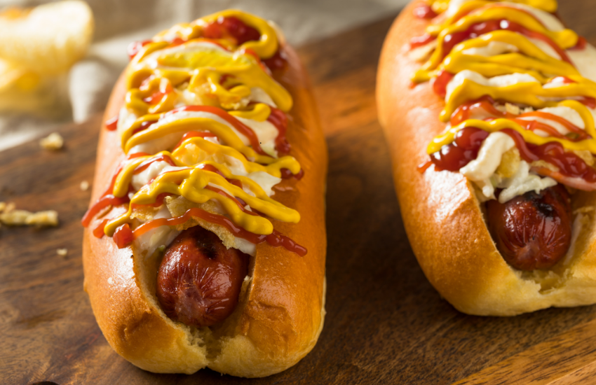 Two hot dogs on a wooden board.