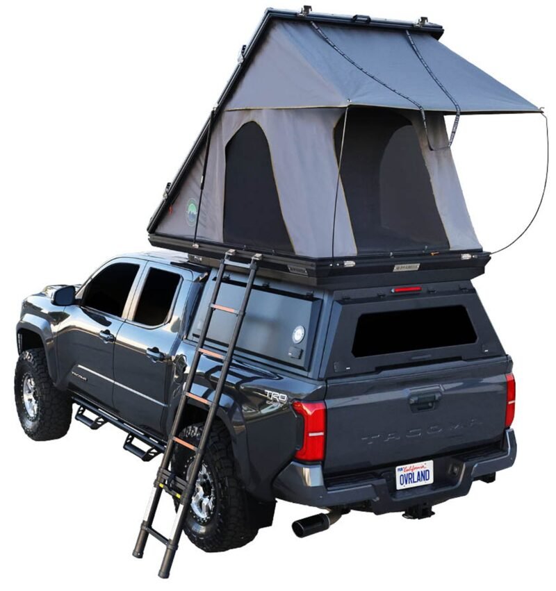 A pick up with a hard shell camper and rooftop tent.