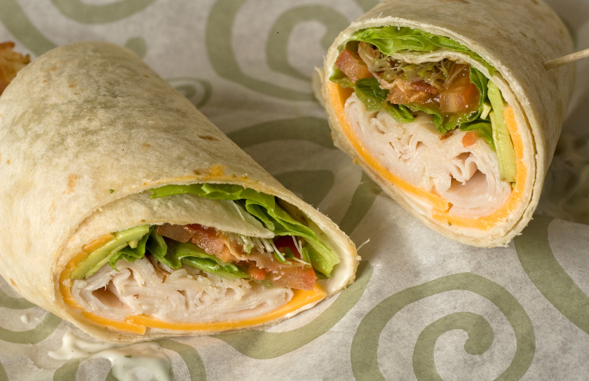 A turkey and cheese wrap on a spiral design table cloth.